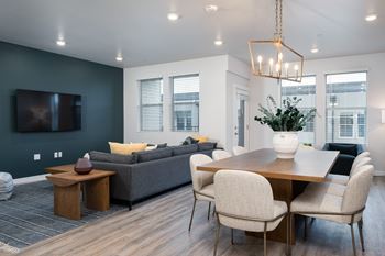 a living and dining room area with a couch table and chairs and a tv on the wall
